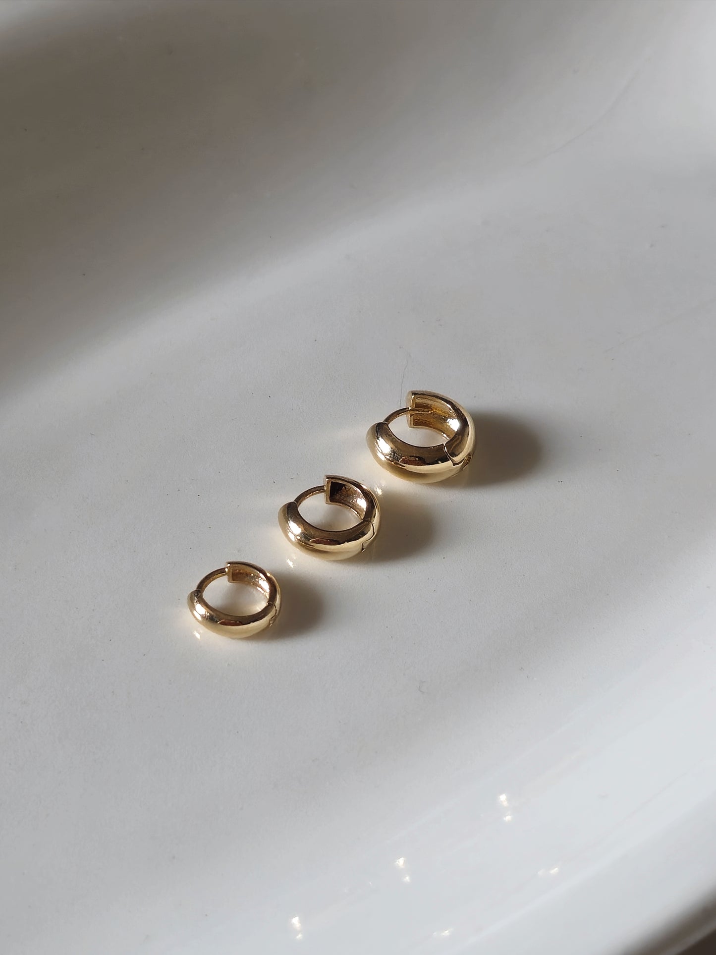14K solid gold Snug-fitting huggie style earring  that sits close to the ear.